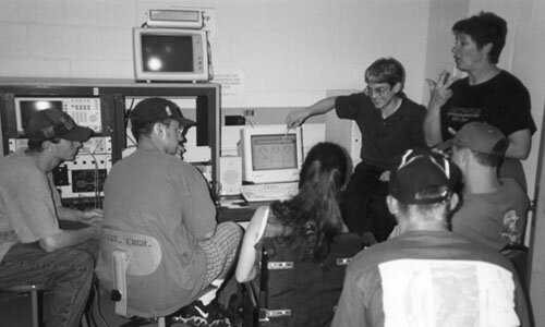 Interpreter in a crowded room with a lot of computer equipment.